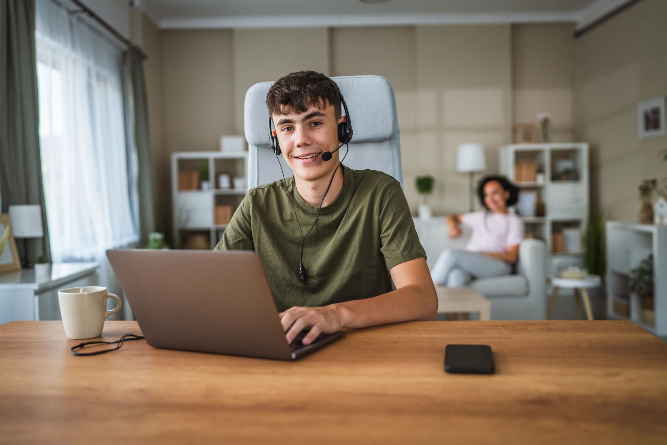 Teenager using a laptop with a headset at home